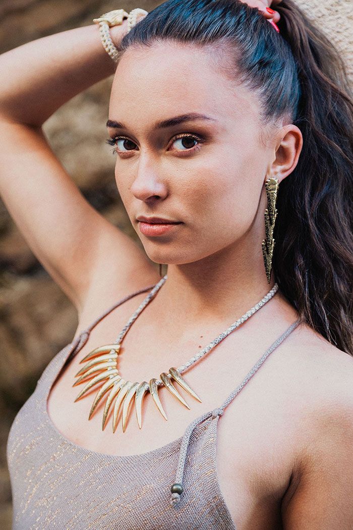 Woman posing with long earrings in the shape of arrowheads